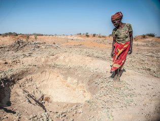 Adelaide Maphangane stands beside an empty water hole in the district of Mabalane, Mozambique.