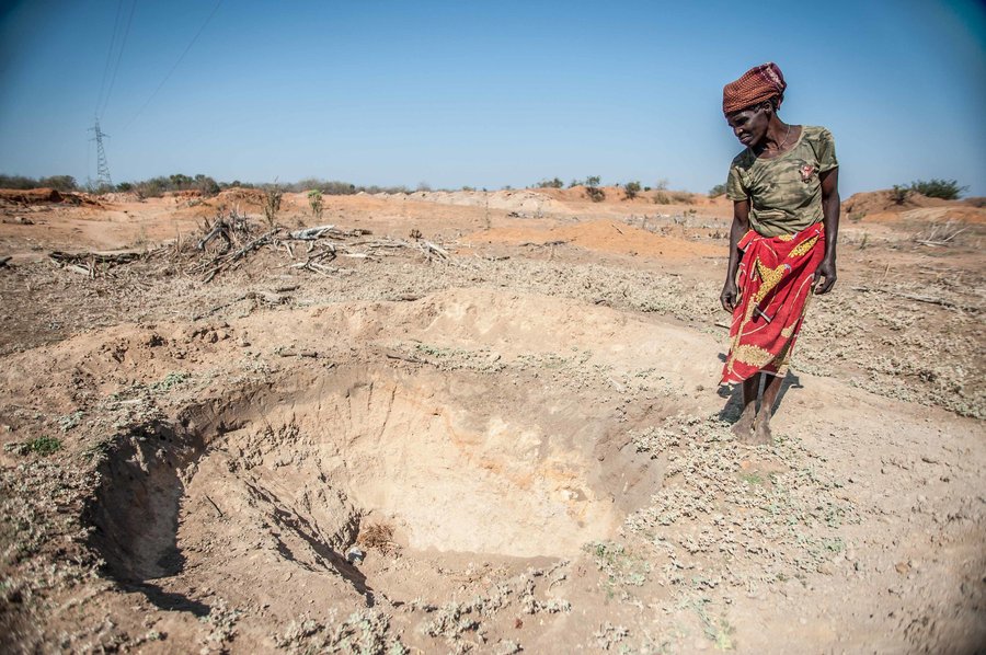 Adelaide Maphangane stands beside an empty water hole in the district of Mabalane, Mozambique.