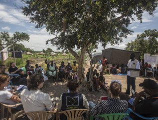 A contingent of European journalists listen to a local liaison officer working with Relief Hope Recovery (GOA), one of several partners of the European Commission’s Civil Protection and Humanitarian Aid department (ECHO) at Rhino refugee settlement.