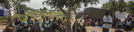 A contingent of European journalists listen to a local liaison officer working with Relief Hope Recovery (GOA), one of several partners of the European Commission’s Civil Protection and Humanitarian Aid department (ECHO) at Rhino refugee settlement.